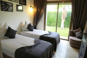 Una habitación de hotel con dos camas y una ventana. en La Rose des Sables, en Marrakech 36 fotos más
