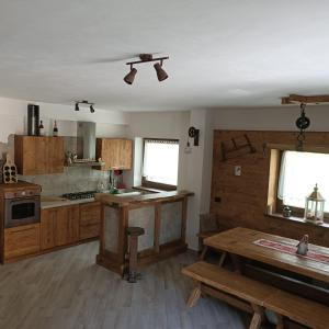 a large kitchen with wooden cabinets and a table at Durmi e Insumiasci in Forni Avoltri