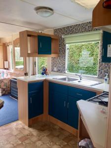 a kitchen with blue cabinets and a sink and a window at Forest View - Adults Only - Maximum 2 Guests in Drumnadrochit