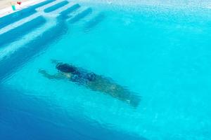 een persoon in het water in een zwembad bij CORFOS BLUE MYKONOS in Ornos