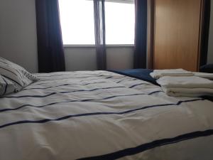 an unmade bed in a room with a window at Casa do Mar in Figueira da Foz