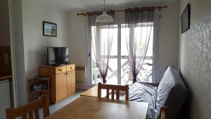een woonkamer met een tafel, een tv en een raam bij REF 042 Appartement T2 avec balcon et piscine Arzon in Arzon