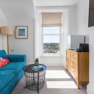 a living room with a blue couch and a window at The Edgcumbe Hotel & DECK Restaurant in Bude