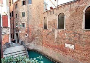 un puente sobre un canal junto a un edificio de ladrillo en Stunning Modern Apartment In The Heart Of Venice, en Venecia