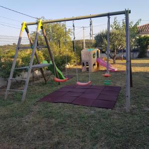a playground with a slide and swings at Gite les Coquelicots in Lédenon