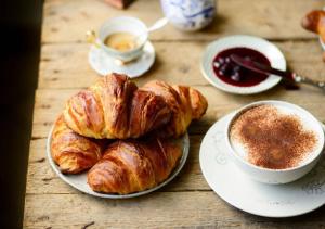 a table topped with plates of croissants and a cup of coffee at La Maison in Mondragone