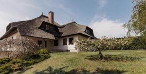 una casa con techo de paja y un árbol en el patio en Ferienhaus Schilfvilla, en Mörbisch am See