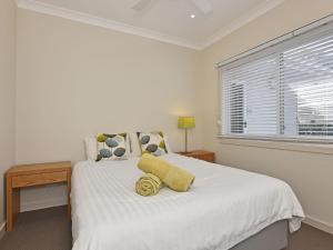 a white bedroom with a large white bed with a window at Wangi Lakehouse in Wangi Wangi