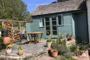 Garden Room in Hockworthy في ويلينغتون: منزل ازرق صغير مع طاولة وبعض النباتات