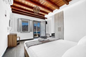 a bedroom with a large white bed and windows at Belvedere in Livadi
