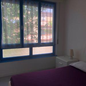 Un dormitorio con dos ventanas y una cama con una colcha morada. en Villa Savoia& Villa Trieste, en Grado