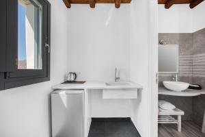 a white bathroom with a sink and a mirror at Belvedere in Livadi
