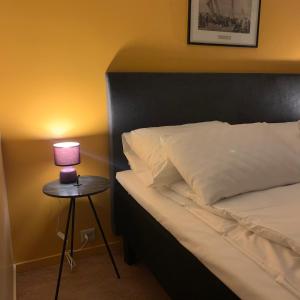 a bed with a lamp on a table next to it at Hattfjelldal Hotell in Hattfjelldal