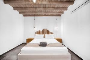a bedroom with a white bed with a wooden ceiling at Belvedere in Livadi