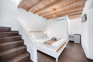 a white bedroom with a bed and stairs at Belvedere in Livadi