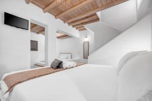 a white bedroom with a bed and a tv at Belvedere in Livadi