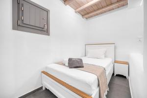 a white bedroom with a bed and a window at Belvedere in Livadi
