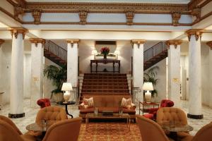 a lobby with couches and chairs and a staircase at Capital Hotel in Little Rock