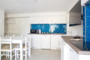 uma cozinha com armários brancos e uma mesa e cadeiras em Casa Janas em Bari Sardo