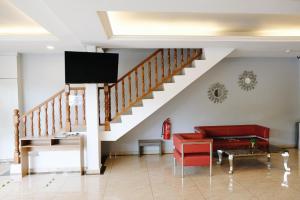 sala de estar con escalera y sofá rojo en Era Plus Hotel, en Seri Kembangan