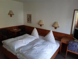 Bett mit weißer Bettwäsche in einem Zimmer in der Unterkunft Gästehaus Endrich in Heidelberg