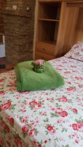 a bed with a green blanket with flowers on it at Monolocale l'Anfiteatro Romano in Assisi
