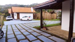 a white car parked in a driveway next to a house at Chalé Villa Magrini in Monte Verde
