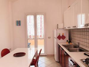 La cuisine blanche est équipée d'un évier et d'un réfrigérateur. dans l'établissement Il Sole, à SantʼAntìoco