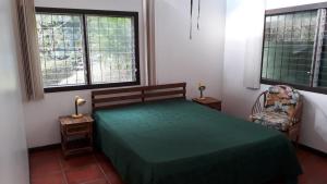 a bedroom with a green bed and two windows at Iguana Libre in Dominical