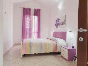 - une chambre avec un lit et une fenêtre avec des rideaux violets dans l'établissement Il Sole, à SantʼAntìoco