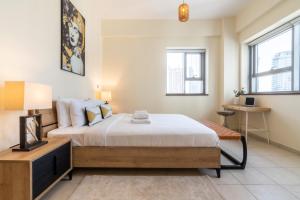 a bedroom with a bed and a table and two windows at Business Bay Apt with Rooftop Pool, Fast WiFi, and near Burj Khalifa in Dubai