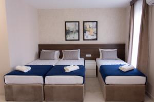 um quarto com 2 camas com lençóis azuis e brancos em Villa BonnaDea em Valjevo