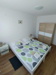 Schlafzimmer mit einem Bett mit einer weißen und grünen Tagesdecke in der Unterkunft Apartmani Valuna in Privlaka