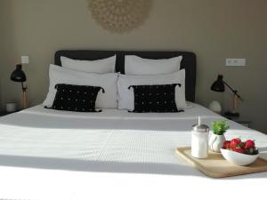 ein Bett mit schwarzen und weißen Kissen und einer Schale Erdbeeren in der Unterkunft Sweet Home studio Aix en Provence, terrasse, piscine, resto, in Aix-en-Provence