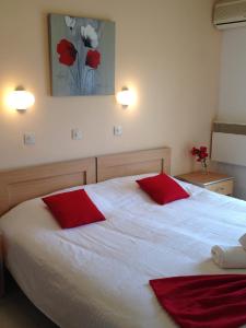 a bedroom with a white bed with red pillows at Zefyros Hotel in Rhodes Town