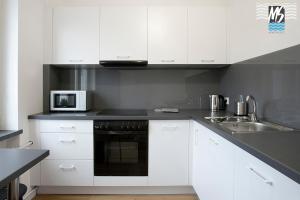 a kitchen with white cabinets and a sink and a microwave at MS Apartments Centrum Gdyni II in Gdynia