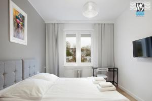 a white bedroom with a bed and a window at MS Apartments Centrum Gdyni II in Gdynia