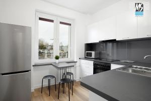 a kitchen with white cabinets and black counter tops at MS Apartments Centrum Gdyni II in Gdynia