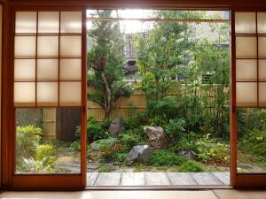 旧鈴木邸 女性専用 في ماتسوياما: مدخل لحديقة ترى من خلال باب مفتوح