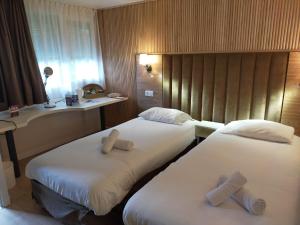 twee bedden in een hotelkamer met handdoeken erop bij The Originals Access, Hôtel Foix (P'tit Dej-Hotel) in Foix