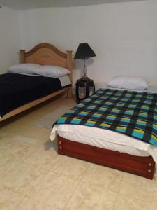 1 dormitorio con 2 camas y una lámpara en el suelo de baldosa en Hostal Naty Luna, en Jardín
