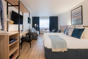 ジョアンヴィル・ル・ポンにあるTulip Residences Joinville-Le-Pontの大きなベッドとデスクが備わるホテルルームです。