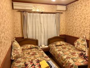 a hotel room with two beds and a window at Pension Puppy Tail in Hakodate