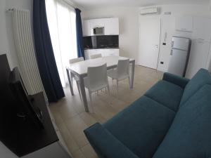 sala de estar con sofá azul, mesa y sillas en Villa Marina Apartments - Agenzia Cocal, en Caorle