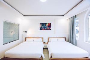 two beds in a room with white walls and windows at TTR An Nam Apart Hotel in Da Lat