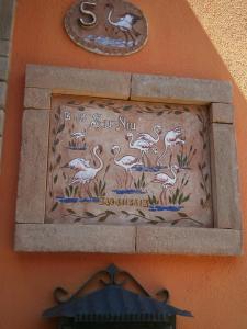 een bord aan de zijkant van een gebouw met vogels erop bij Bed and Breakfast Su Niu in Quartucciu