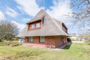 a house with a thatched roof with a bicycle in front at Munkmarscher Chaussee 11 Whg 22 in Keitum