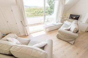 a living room with two white couches and a large window at Soenshoern Whg 6 in Munkmarsch