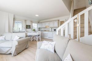 ein Wohnzimmer mit weißen Möbeln und eine Küche in der Unterkunft Soenshoern Whg 6 in Munkmarsch