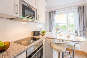 a kitchen with white cabinets and a counter top at Inseloase Ostertresker 54 in Tinnum